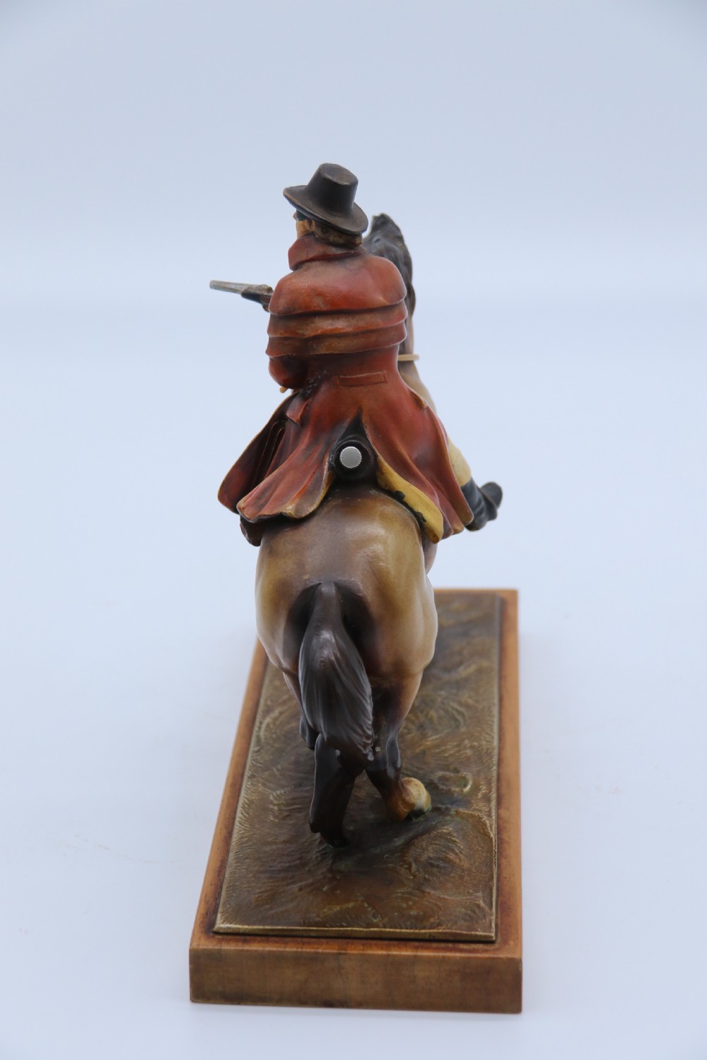 An Art Deco cold-painted metal figure of a masked highwayman on horseback mounted on a rectangular wooden plinth, featuring an integrated table lighter mechanism. View III