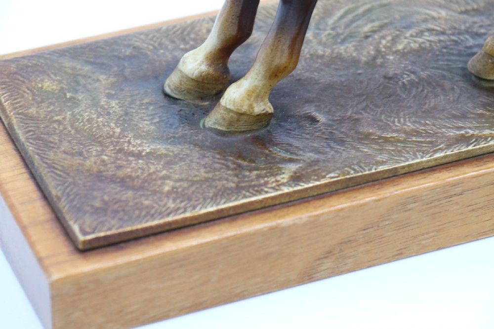 An Art Deco cold-painted metal figure of a masked highwayman on horseback mounted on a rectangular wooden plinth, featuring an integrated table lighter mechanism. View XI