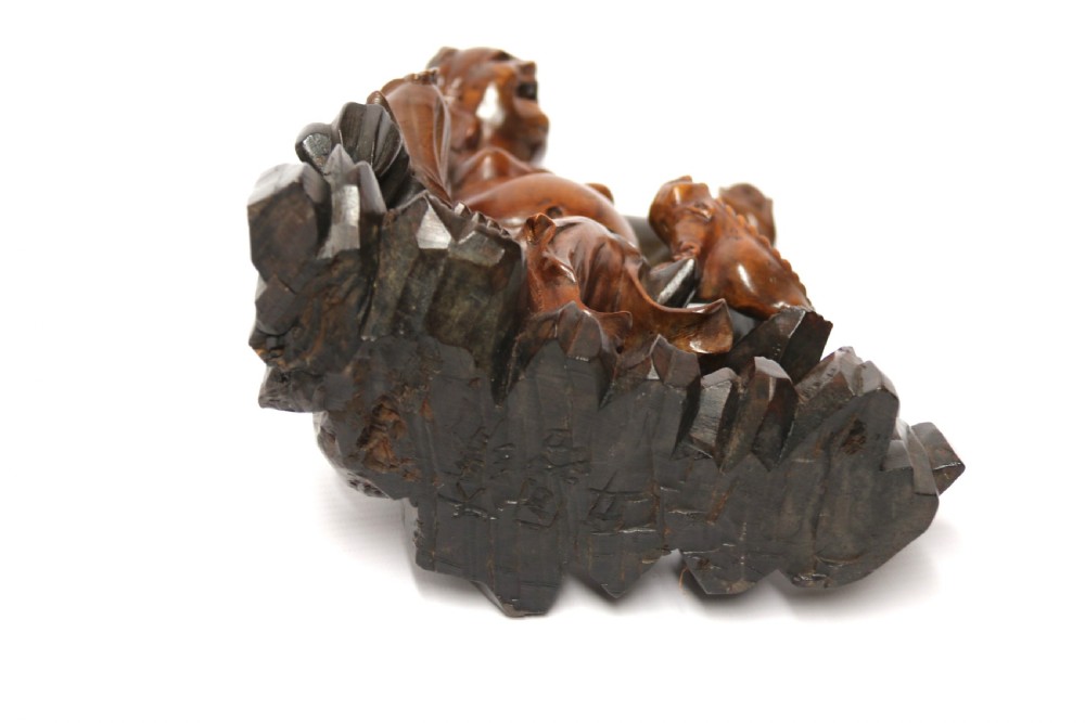 A late nineteenth-century carved brown hardwood figure depicting a seated laughing figure with an open mouth alongside a small mythical creature on a carved rocky base. View XI