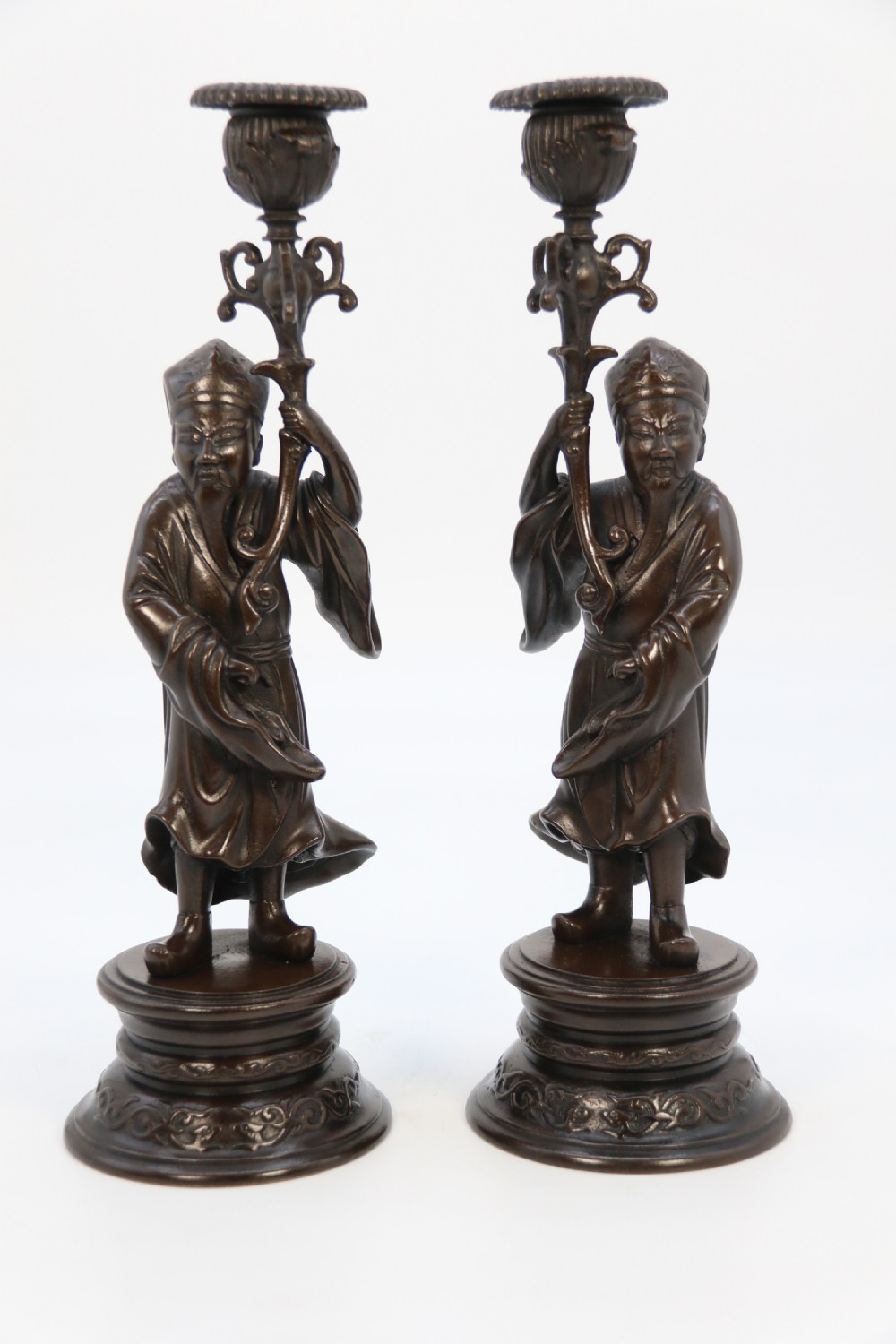 A pair of 19th-century French dark bronze candlesticks sculpted as standing Chinese figures holding flower-shaped candle nozzles on stepped round bases. View XV