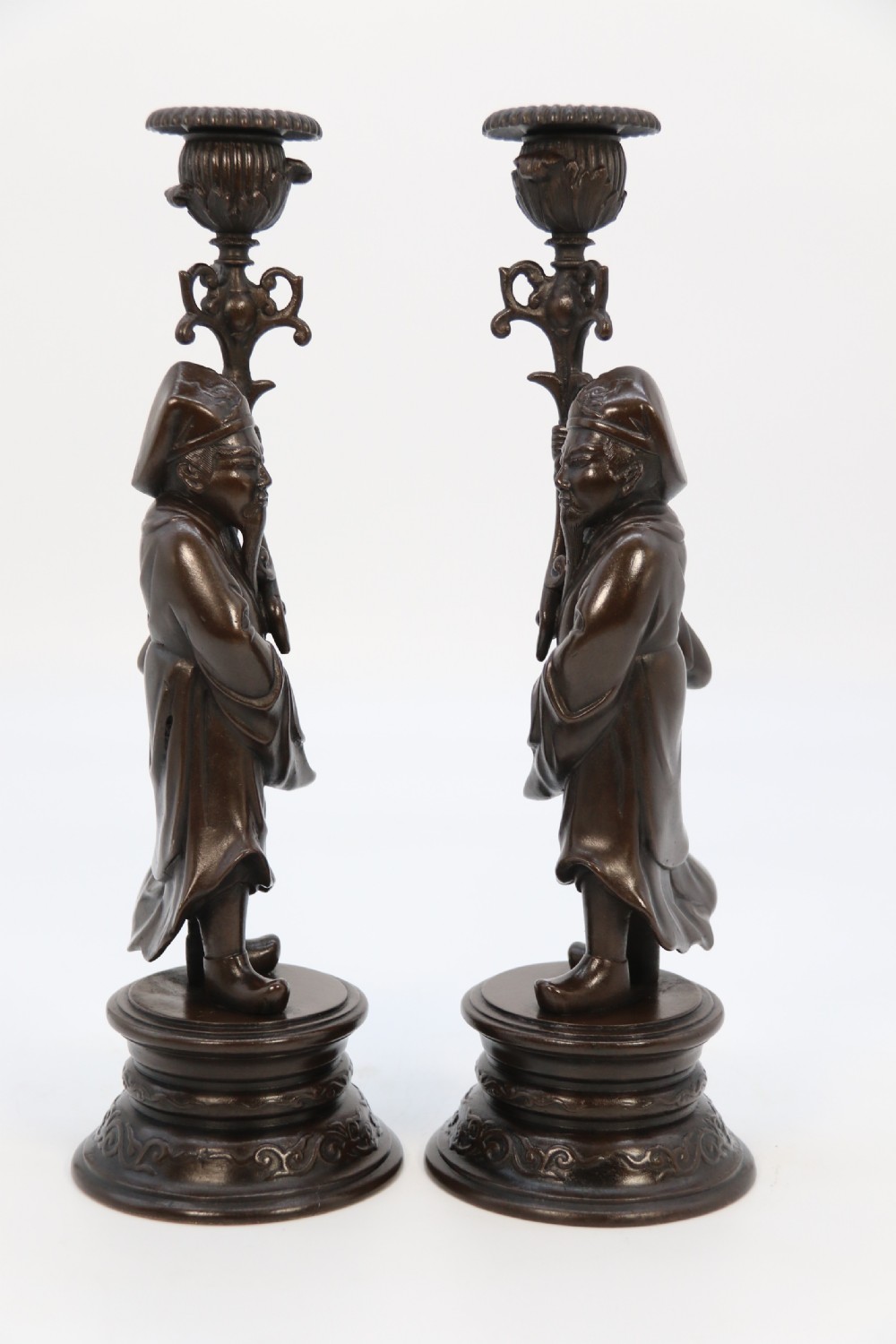 A pair of 19th-century French dark bronze candlesticks sculpted as standing Chinese figures holding flower-shaped candle nozzles on stepped round bases. View XVII