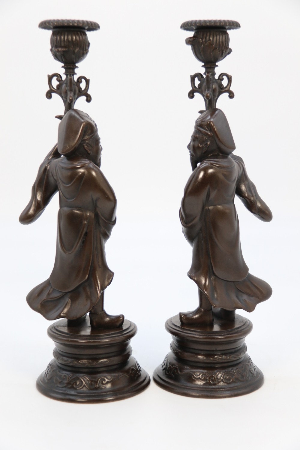 A pair of 19th-century French dark bronze candlesticks sculpted as standing Chinese figures holding flower-shaped candle nozzles on stepped round bases. View XVIII