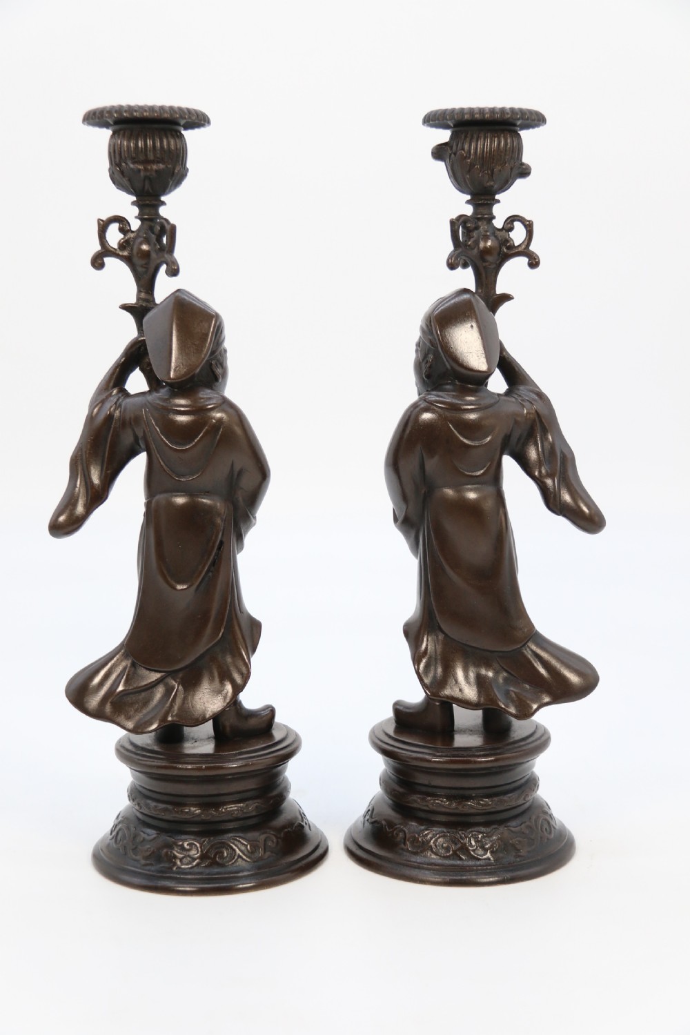 A pair of 19th-century French dark bronze candlesticks sculpted as standing Chinese figures holding flower-shaped candle nozzles on stepped round bases. View XIX