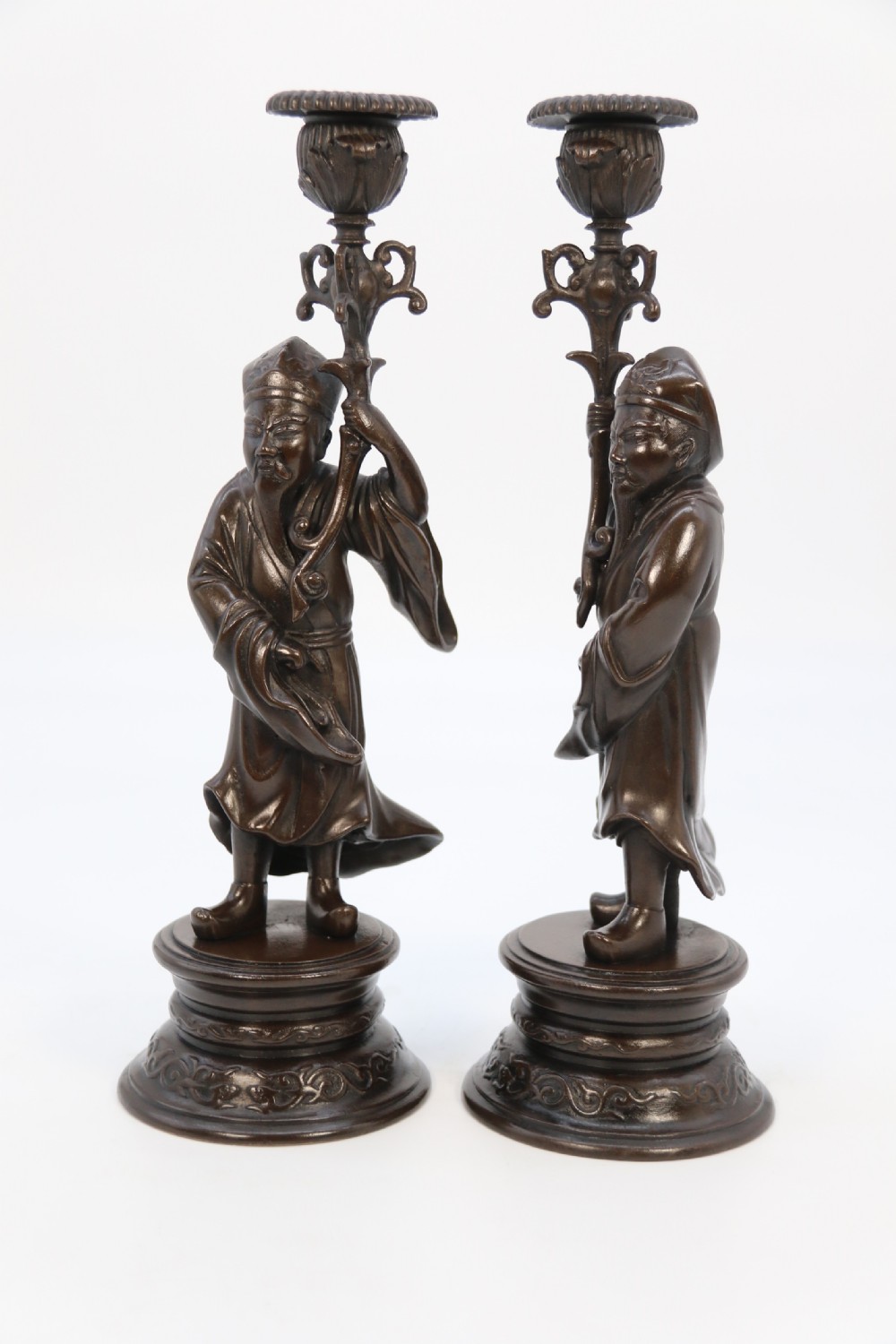 A pair of 19th-century French dark bronze candlesticks sculpted as standing Chinese figures holding flower-shaped candle nozzles on stepped round bases. View XXI