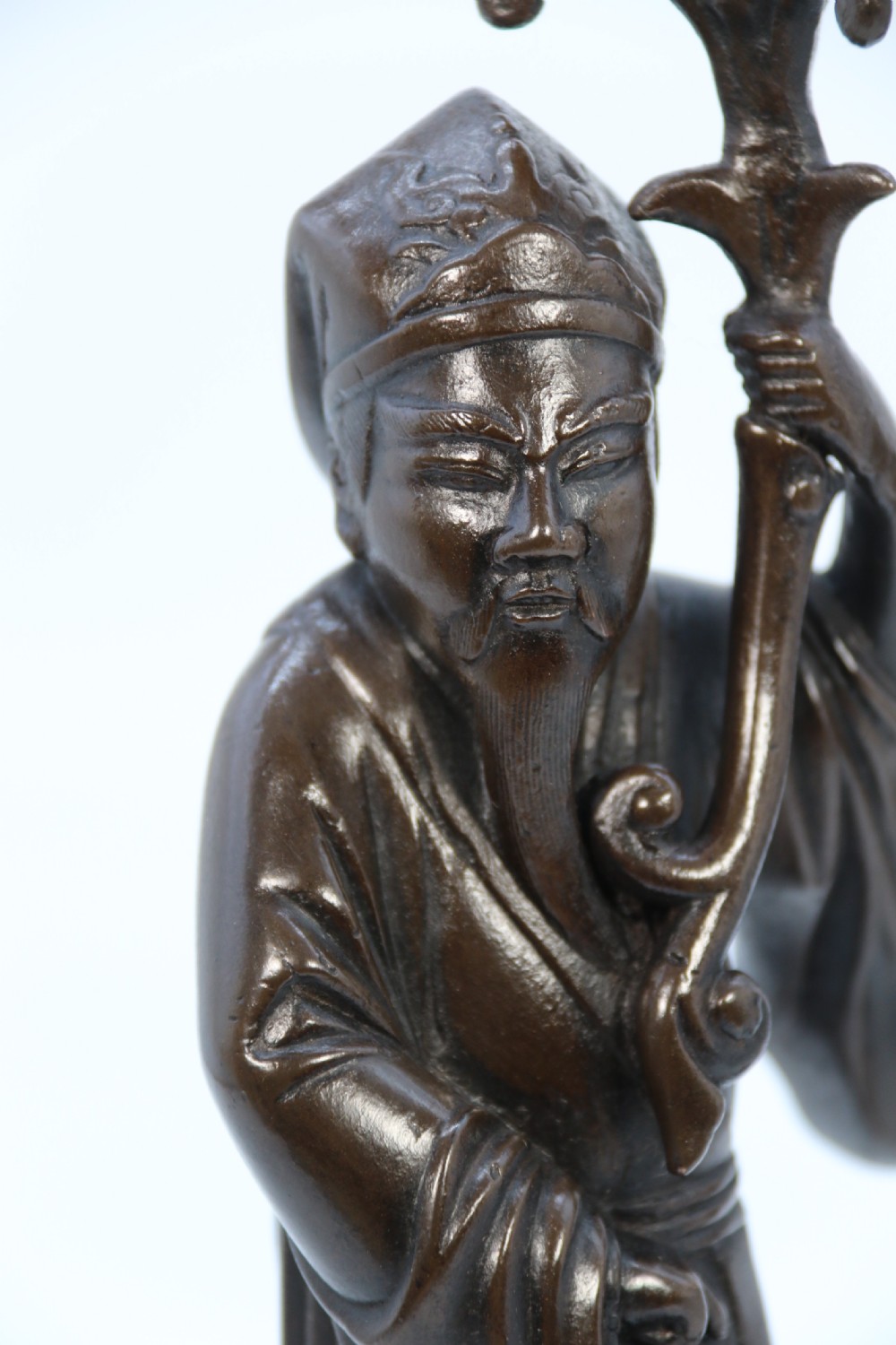 A pair of 19th-century French dark bronze candlesticks sculpted as standing Chinese figures holding flower-shaped candle nozzles on stepped round bases. View XXII