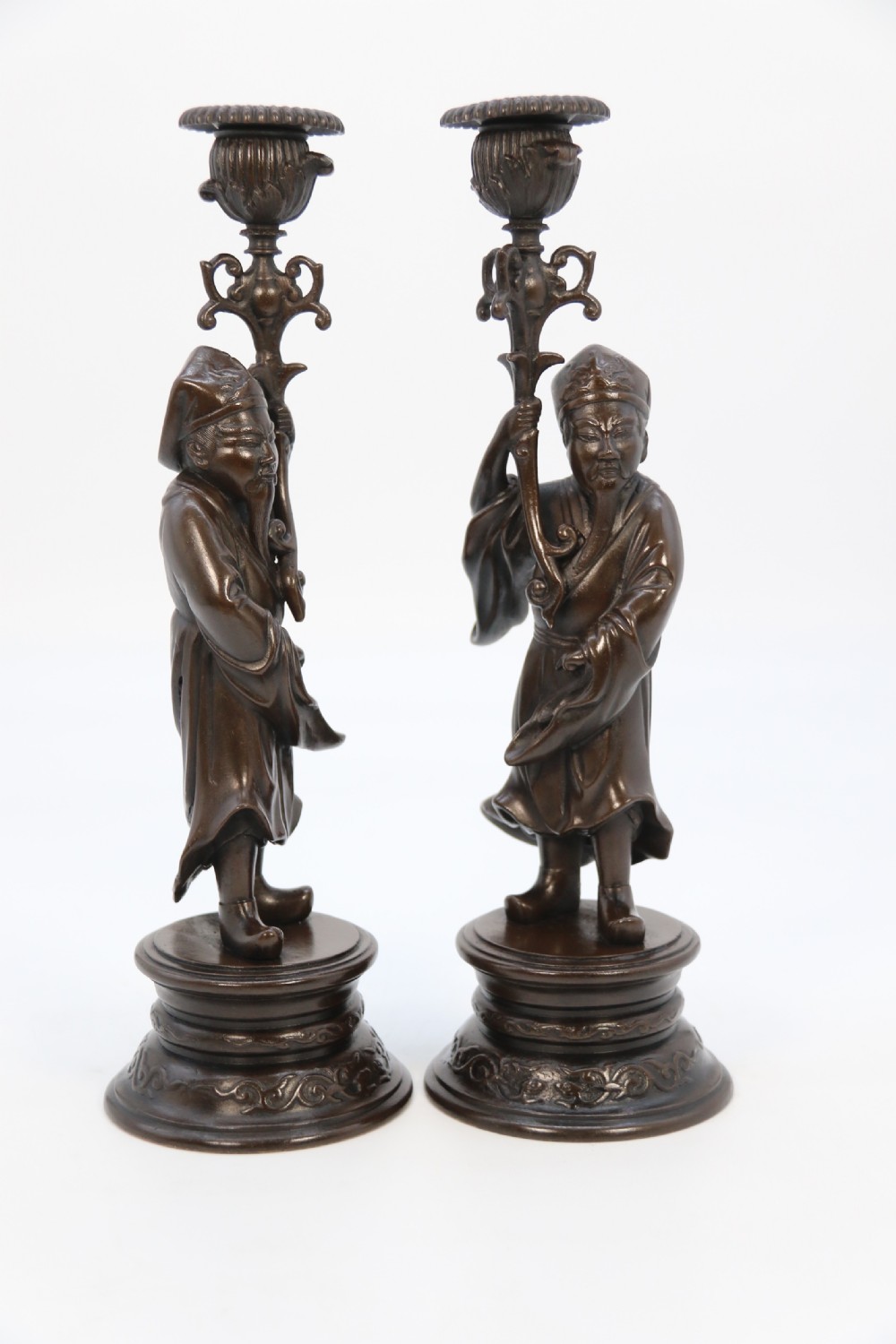 A pair of 19th-century French dark bronze candlesticks sculpted as standing Chinese figures holding flower-shaped candle nozzles on stepped round bases. View XXIII