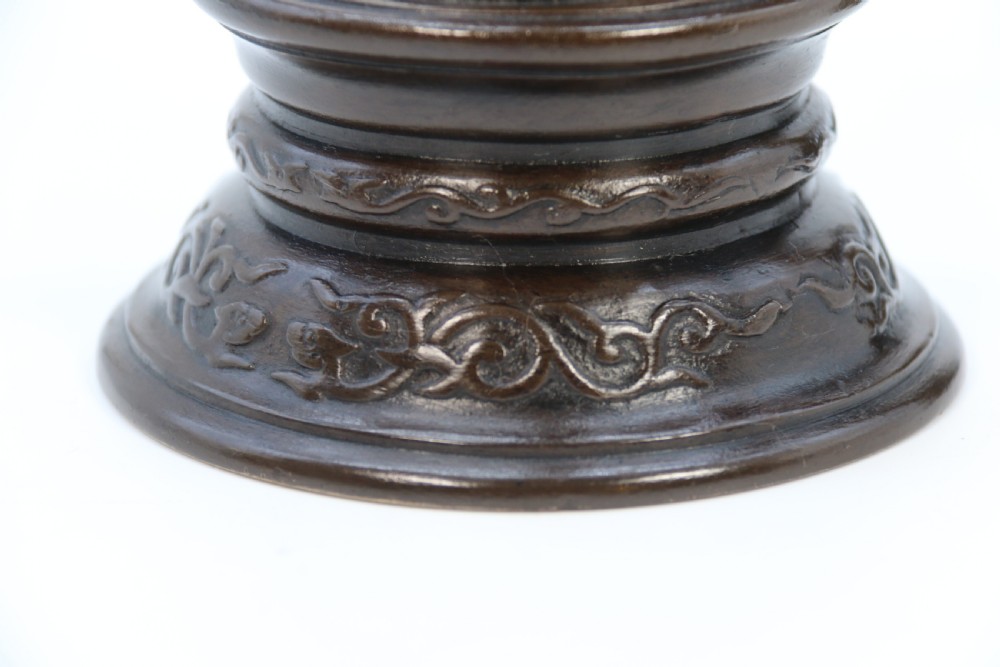 A pair of 19th-century French dark bronze candlesticks sculpted as standing Chinese figures holding flower-shaped candle nozzles on stepped round bases. View XXV
