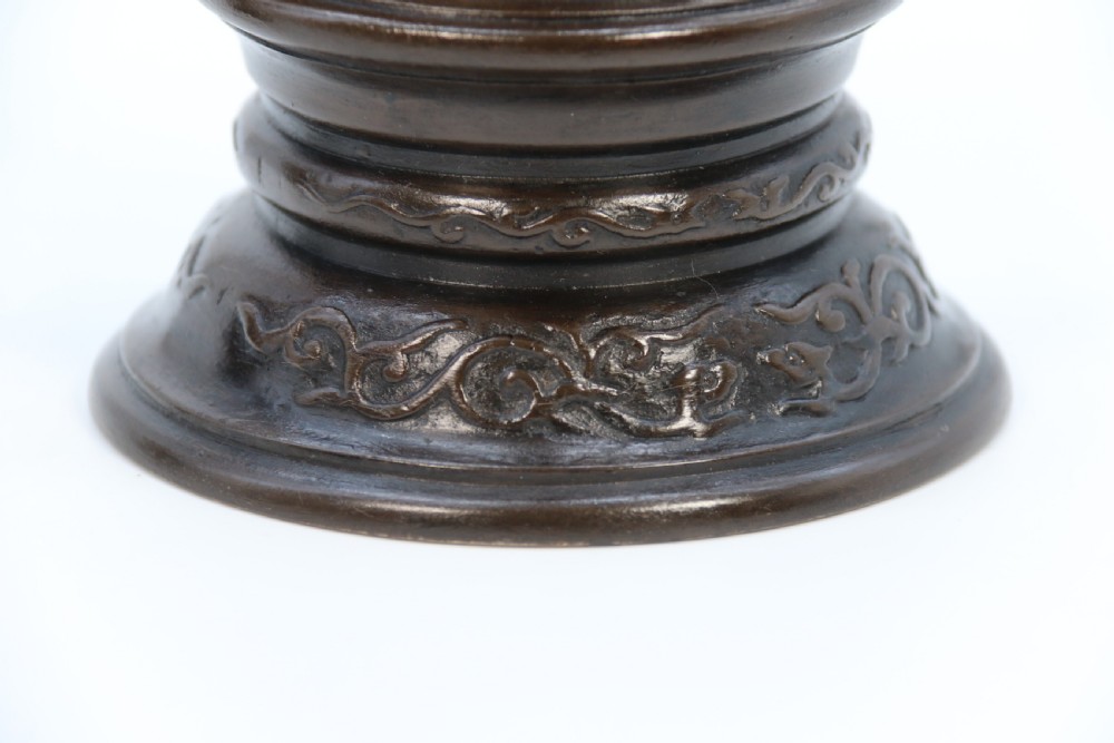 A pair of 19th-century French dark bronze candlesticks sculpted as standing Chinese figures holding flower-shaped candle nozzles on stepped round bases. View XXIX
