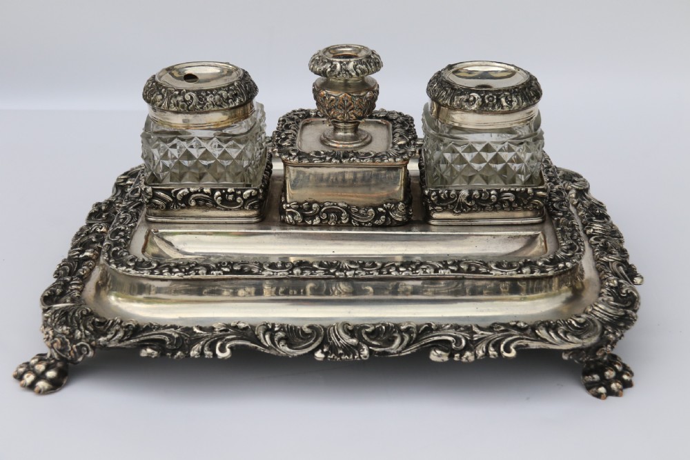 An early nineteenth-century Sheffield plate desk inkstand featuring two cut-glass inkwells and decorative scroll borders raised on paw feet. View VI