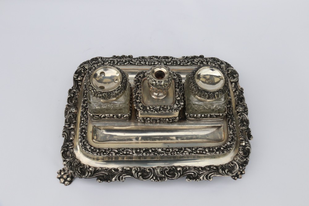 An early nineteenth-century Sheffield plate desk inkstand featuring two cut-glass inkwells and decorative scroll borders raised on paw feet. View VIII