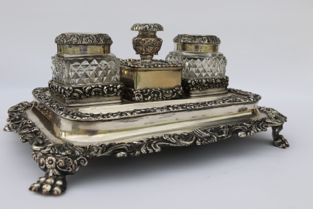 An early nineteenth-century Sheffield plate desk inkstand featuring two cut-glass inkwells and decorative scroll borders raised on paw feet. View IX