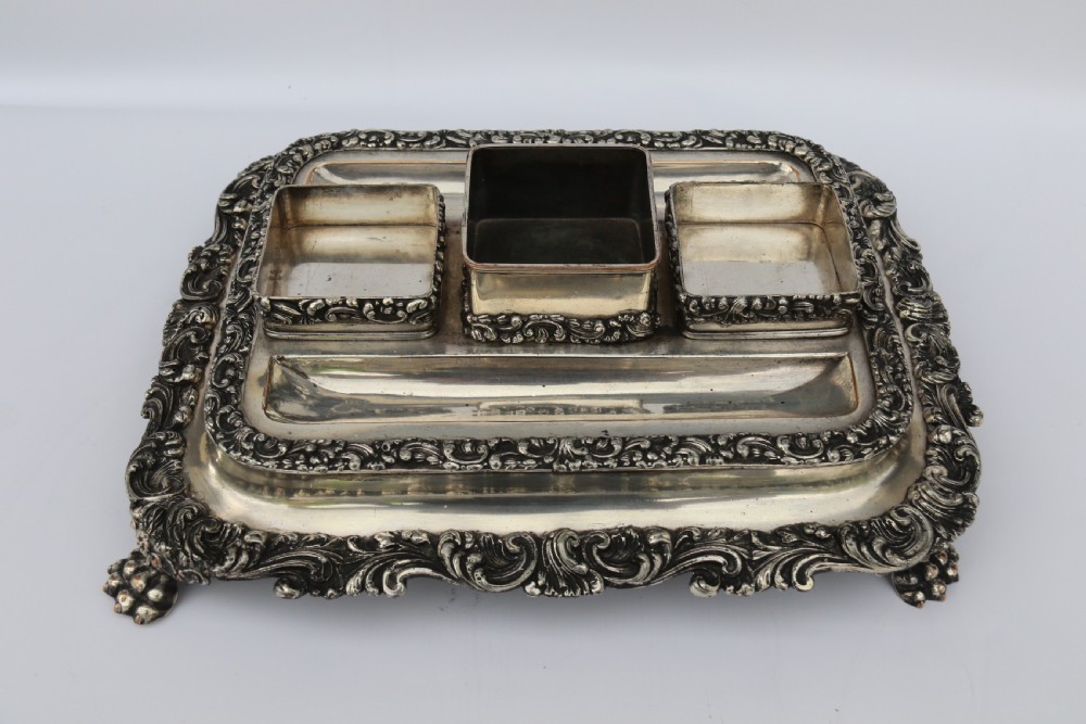 An early nineteenth-century Sheffield plate desk inkstand featuring two cut-glass inkwells and decorative scroll borders raised on paw feet. View XI