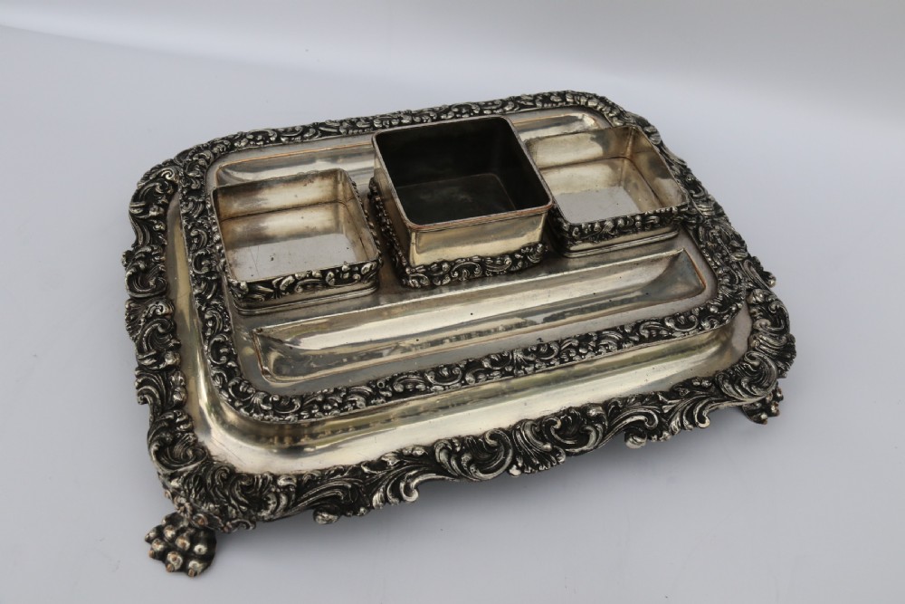 An early nineteenth-century Sheffield plate desk inkstand featuring two cut-glass inkwells and decorative scroll borders raised on paw feet. View XII