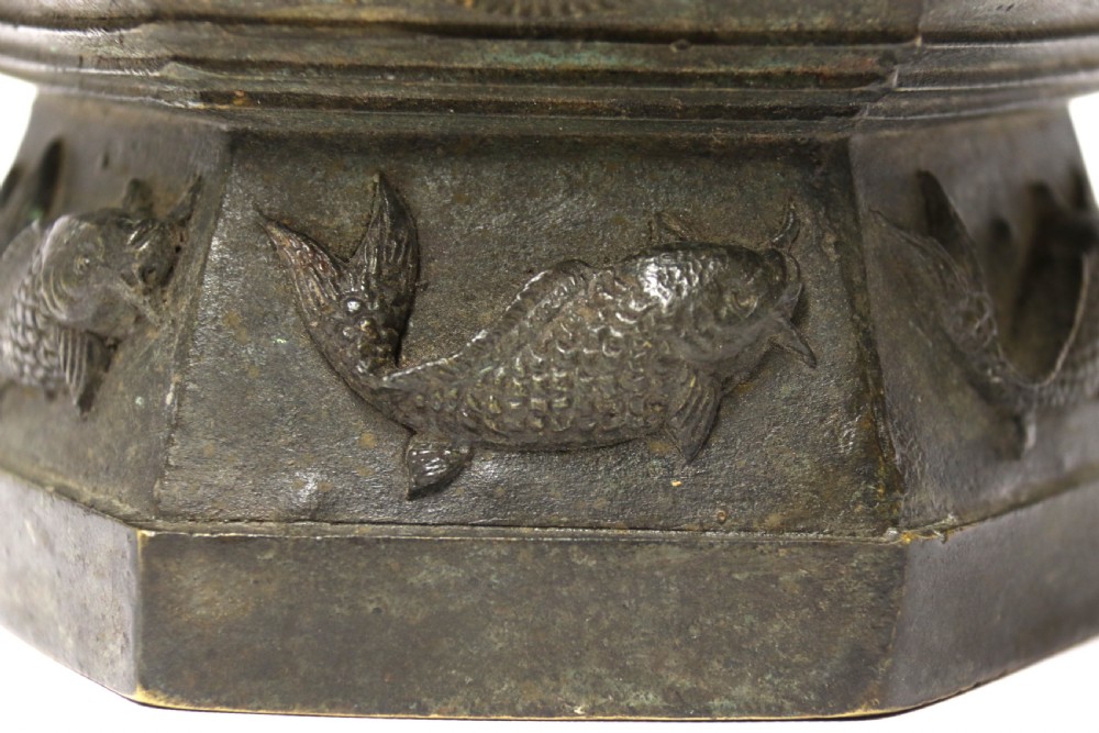 A hexagonal dark bronze Chinese vessel featuring cast relief decoration of fish, pagodas, and floral neck bands with twin side handles. View VI