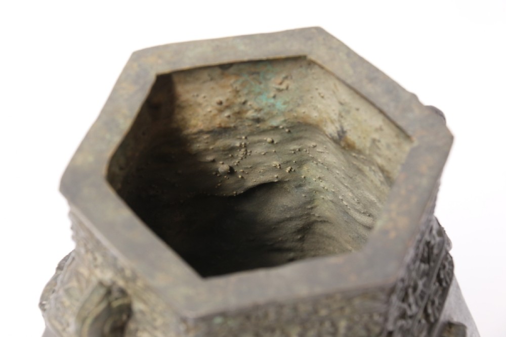 A hexagonal dark bronze Chinese vessel featuring cast relief decoration of fish, pagodas, and floral neck bands with twin side handles. View XIII
