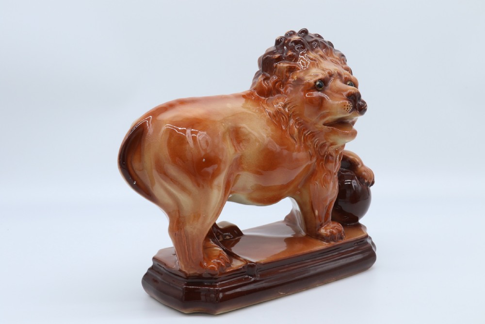 A pair of warm brown glazed earthenware Medici lion figurines standing on integral bases with one front paw resting on a ball. View VIII