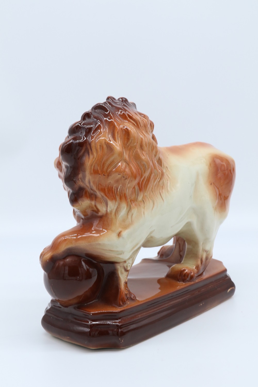 A pair of warm brown glazed earthenware Medici lion figurines standing on integral bases with one front paw resting on a ball. View IX