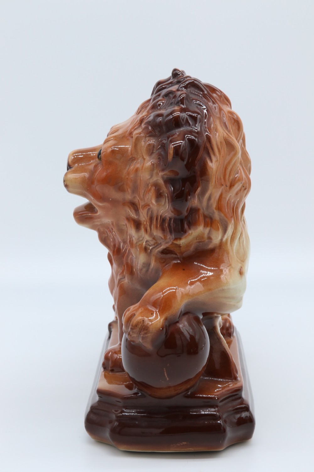 A pair of warm brown glazed earthenware Medici lion figurines standing on integral bases with one front paw resting on a ball. View XIII