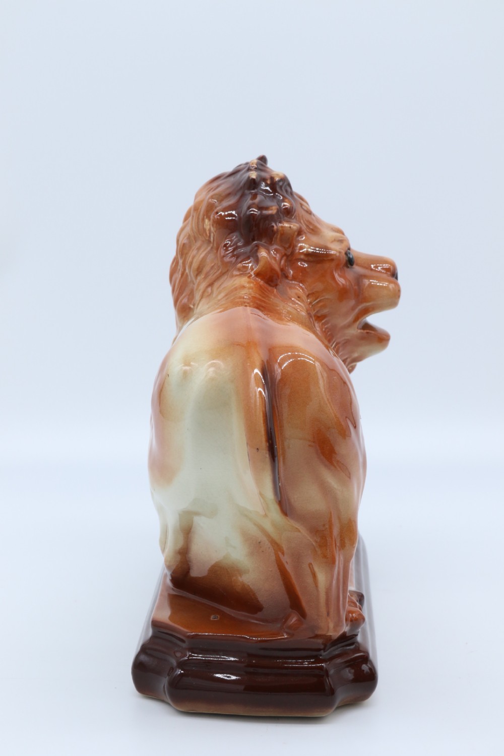 A pair of warm brown glazed earthenware Medici lion figurines standing on integral bases with one front paw resting on a ball. View XIV