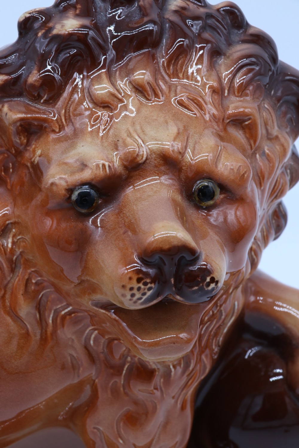 A pair of warm brown glazed earthenware Medici lion figurines standing on integral bases with one front paw resting on a ball. View XVI