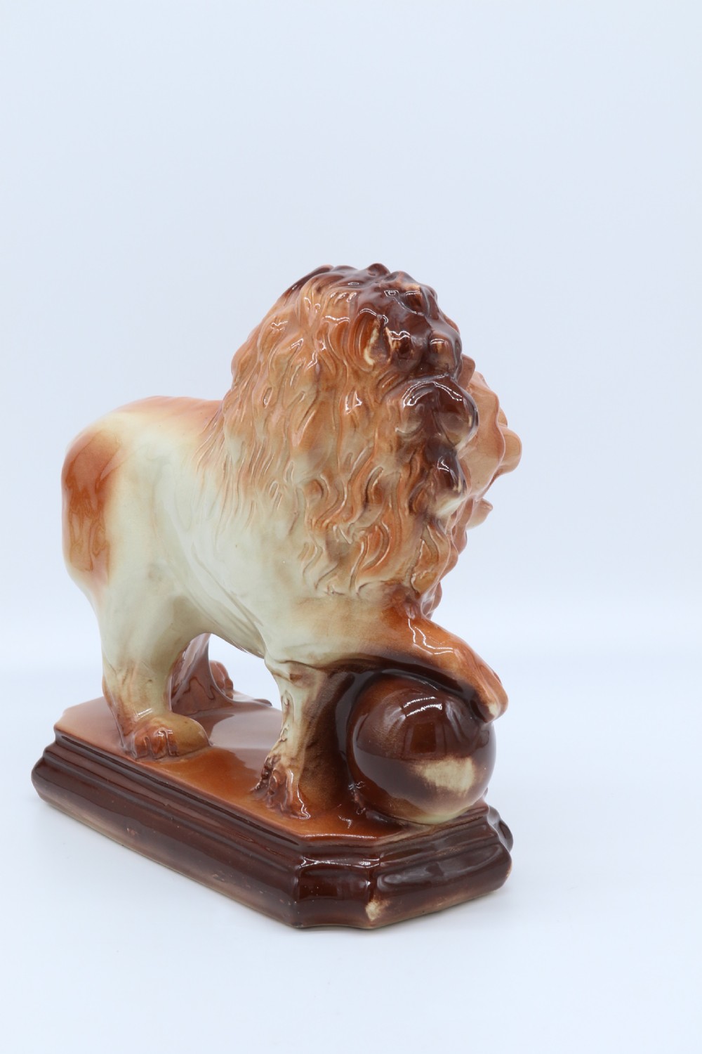 A pair of warm brown glazed earthenware Medici lion figurines standing on integral bases with one front paw resting on a ball. View XXII