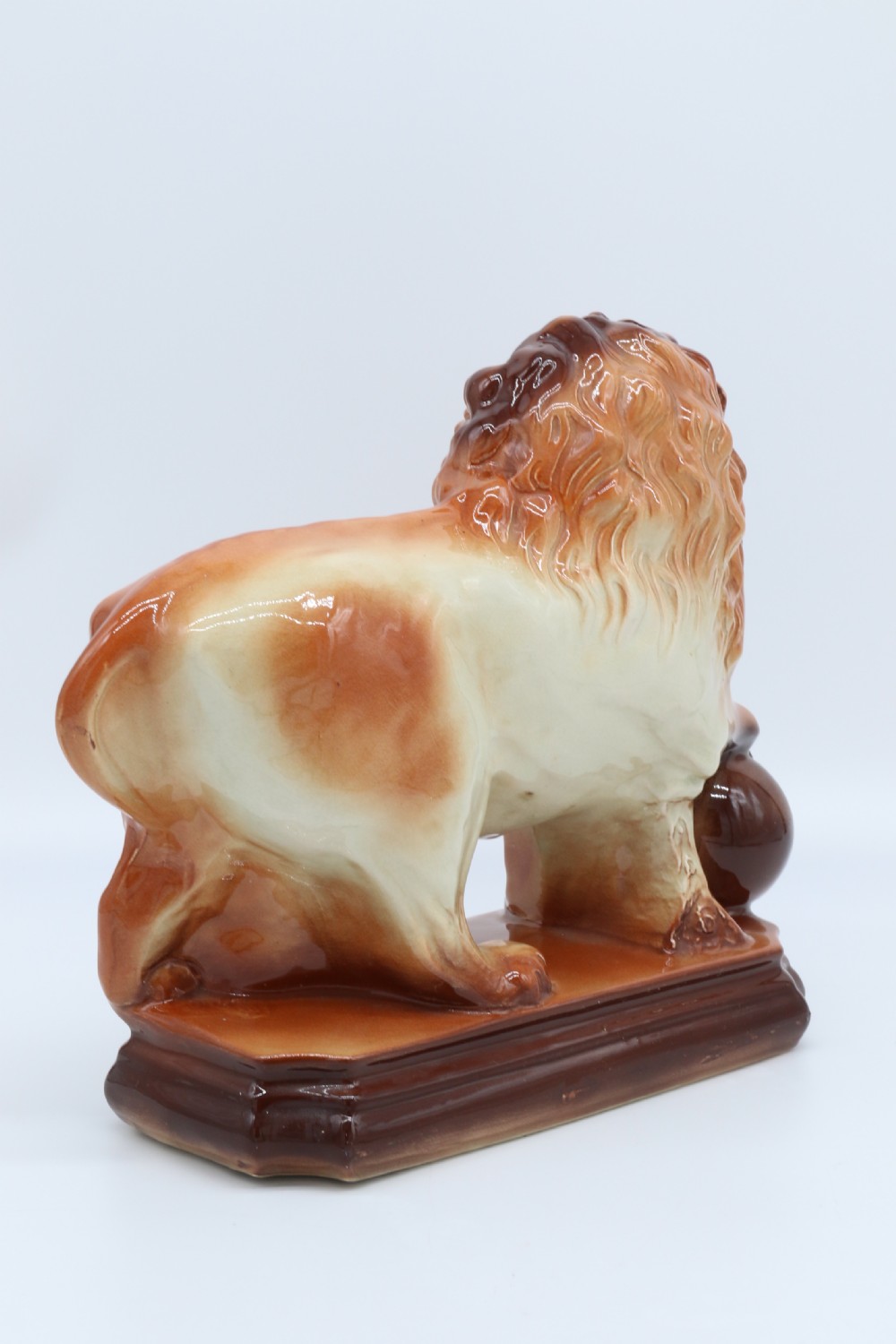 A pair of warm brown glazed earthenware Medici lion figurines standing on integral bases with one front paw resting on a ball. View XXIV