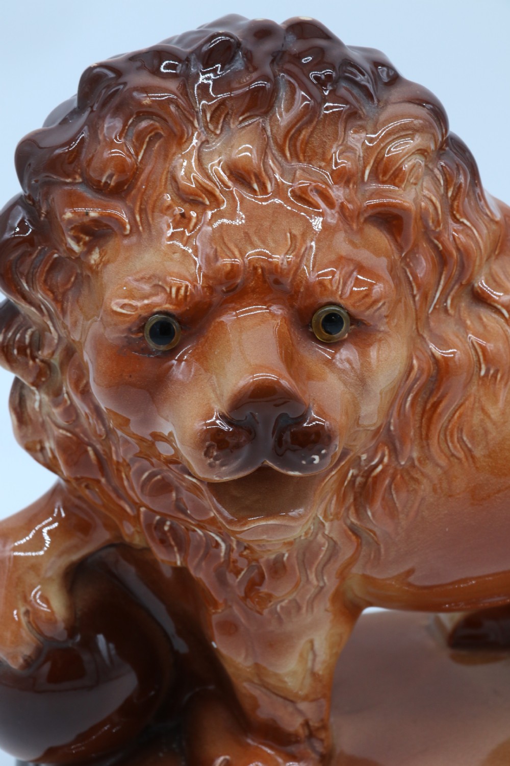 A pair of warm brown glazed earthenware Medici lion figurines standing on integral bases with one front paw resting on a ball. View XXVI