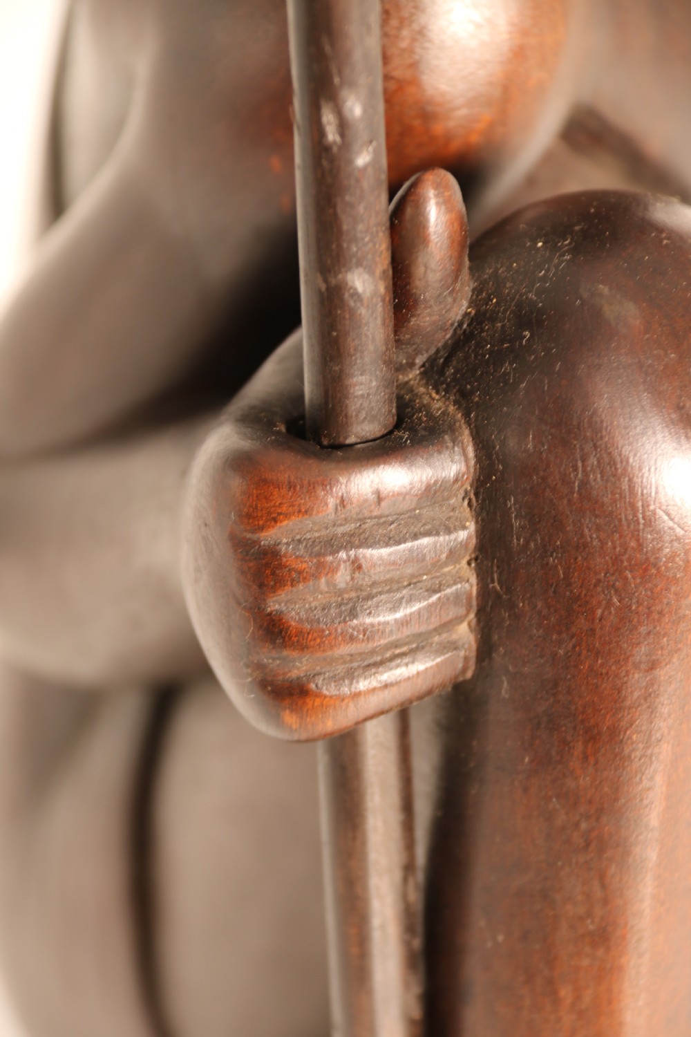 A dark hardwood hand-carved sculpture of a kneeling Maasai warrior holding a spear and club on an integrated wooden base. View XX