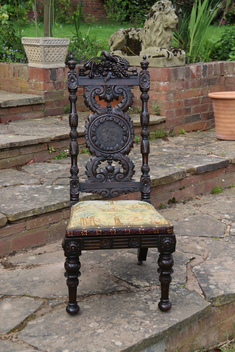 A 19th-century high-backed dark walnut chair featuring intricate floral, bird, and acanthus leaf wood carvings and a patterned upholstered seat. View III