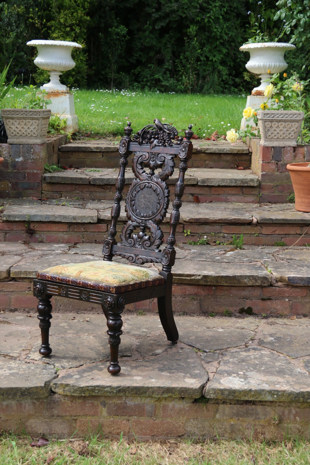 A 19th-century high-backed dark walnut chair featuring intricate floral, bird, and acanthus leaf wood carvings and a patterned upholstered seat. View IV