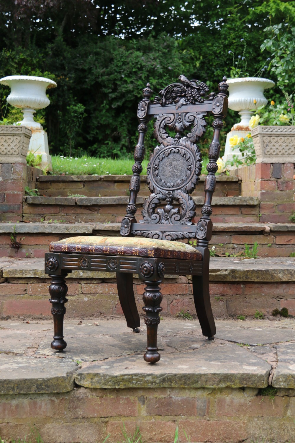A 19th-century high-backed dark walnut chair featuring intricate floral, bird, and acanthus leaf wood carvings and a patterned upholstered seat. View VII