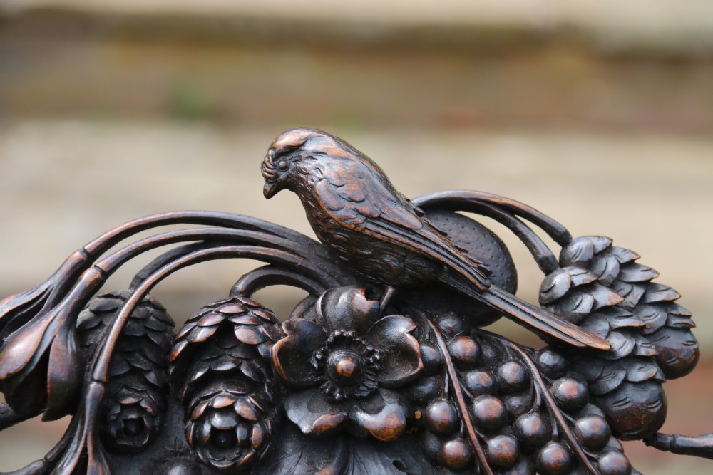 A 19th-century high-backed dark walnut chair featuring intricate floral, bird, and acanthus leaf wood carvings and a patterned upholstered seat. View VIII
