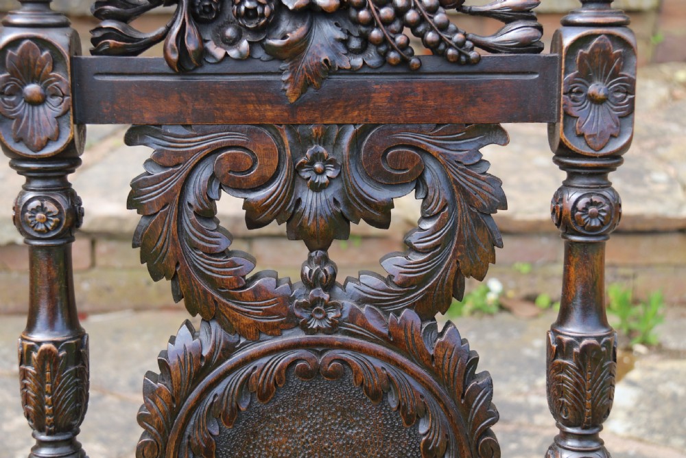 A 19th-century high-backed dark walnut chair featuring intricate floral, bird, and acanthus leaf wood carvings and a patterned upholstered seat. View IX