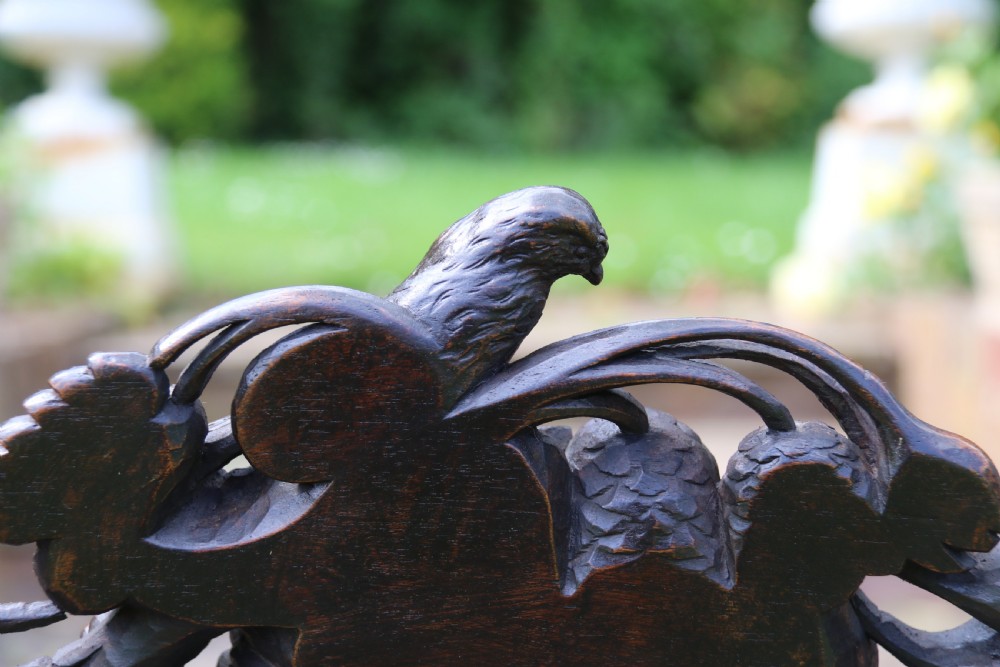 A 19th-century high-backed dark walnut chair featuring intricate floral, bird, and acanthus leaf wood carvings and a patterned upholstered seat. View XI