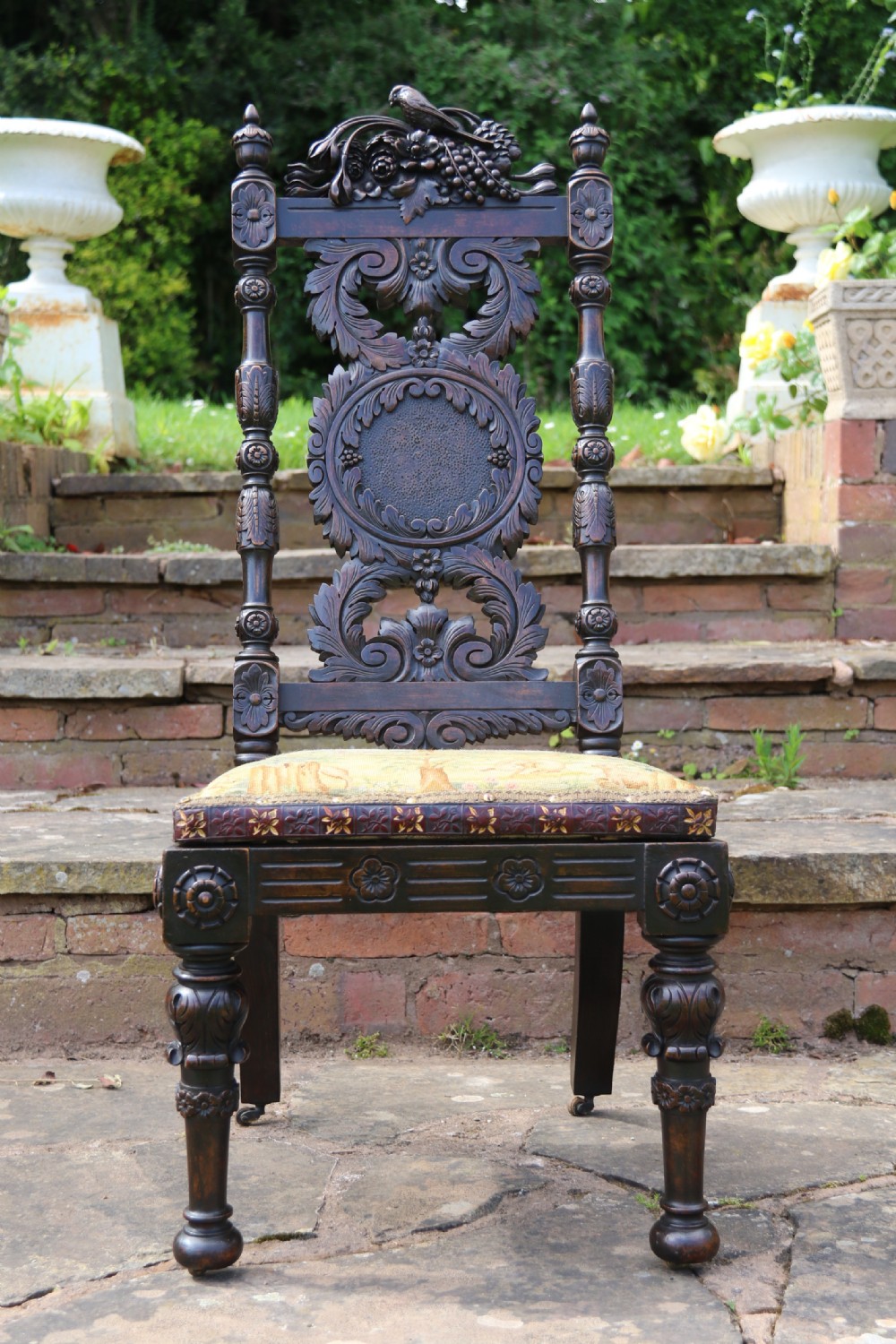A 19th-century high-backed dark walnut chair featuring intricate floral, bird, and acanthus leaf wood carvings and a patterned upholstered seat. View XIII
