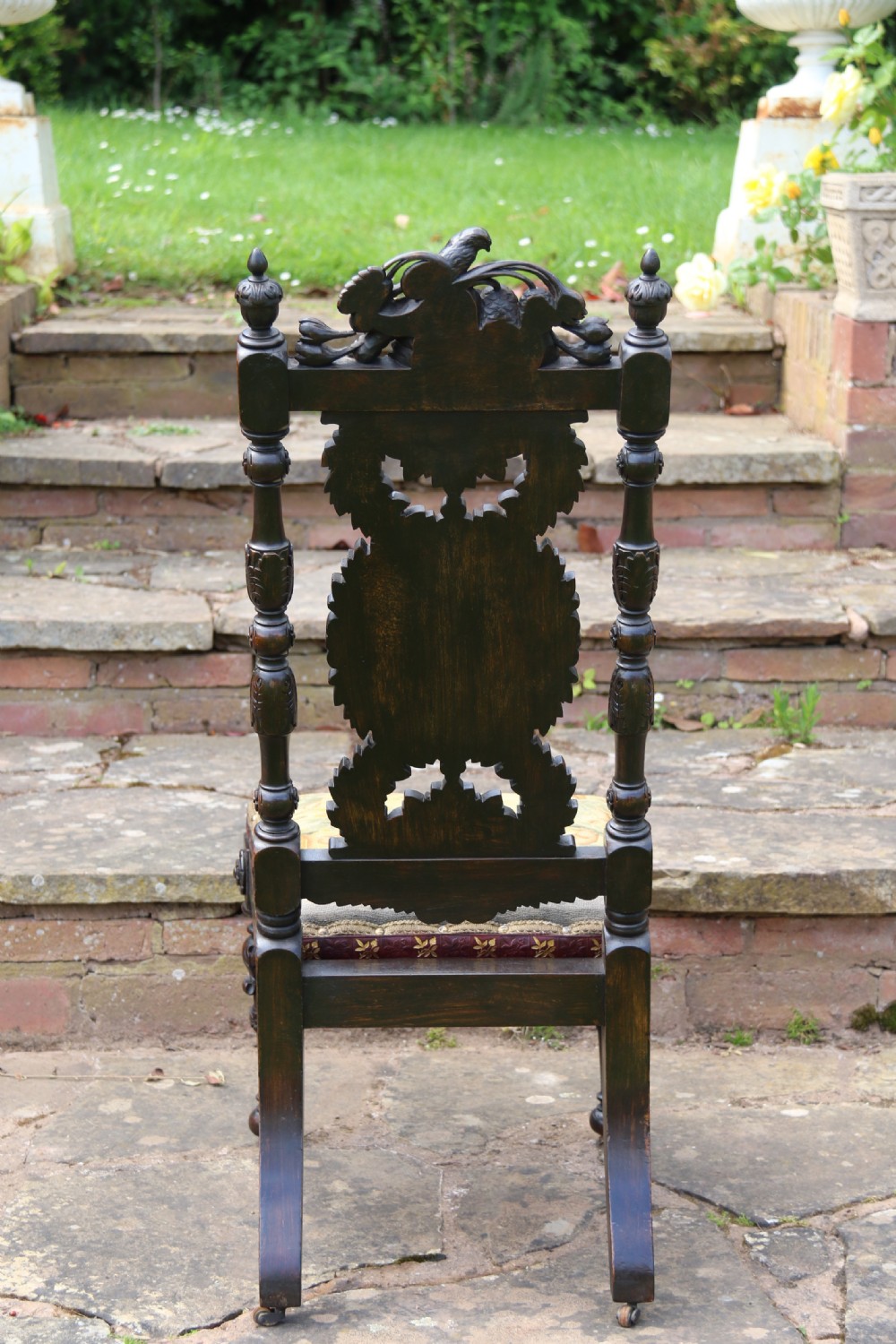 A 19th-century high-backed dark walnut chair featuring intricate floral, bird, and acanthus leaf wood carvings and a patterned upholstered seat. View XIV