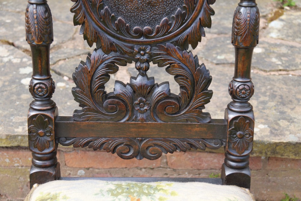 A 19th-century high-backed dark walnut chair featuring intricate floral, bird, and acanthus leaf wood carvings and a patterned upholstered seat. View XVIII