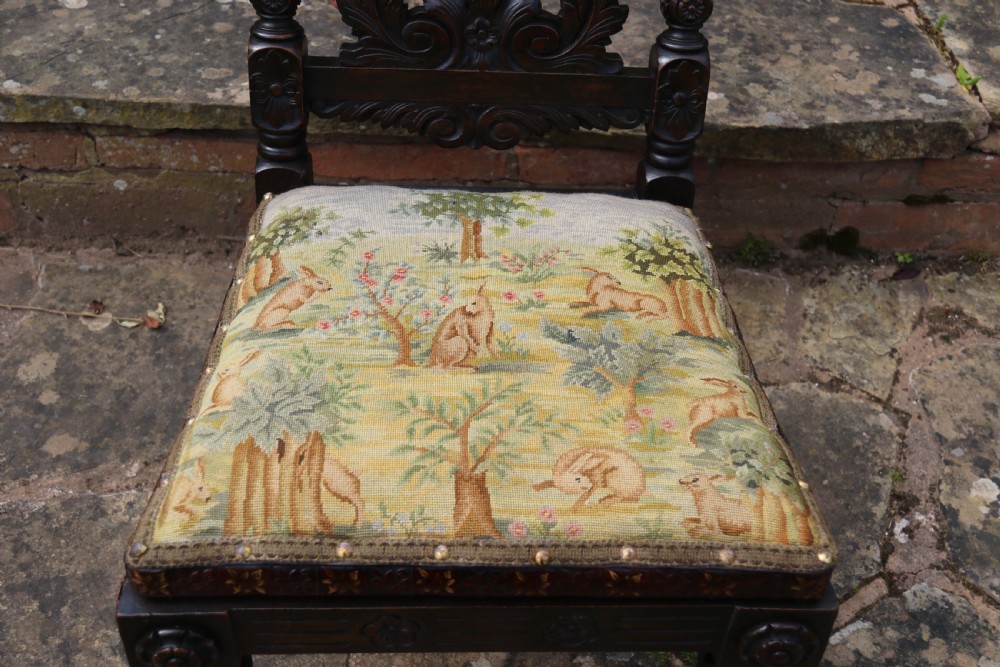 A 19th-century high-backed dark walnut chair featuring intricate floral, bird, and acanthus leaf wood carvings and a patterned upholstered seat. View XIX