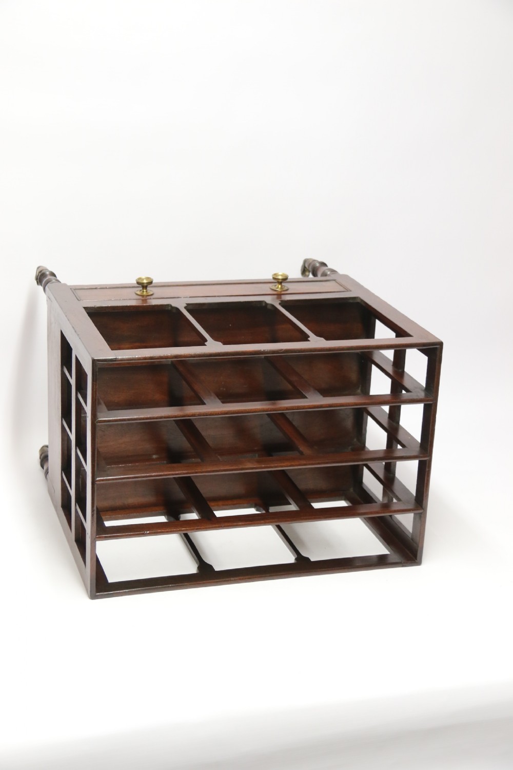 A dark mahogany George III Canterbury featuring slatted vertical partitions, a lower single drawer with brass ring handles, and turned legs resting on brass castors. View VI