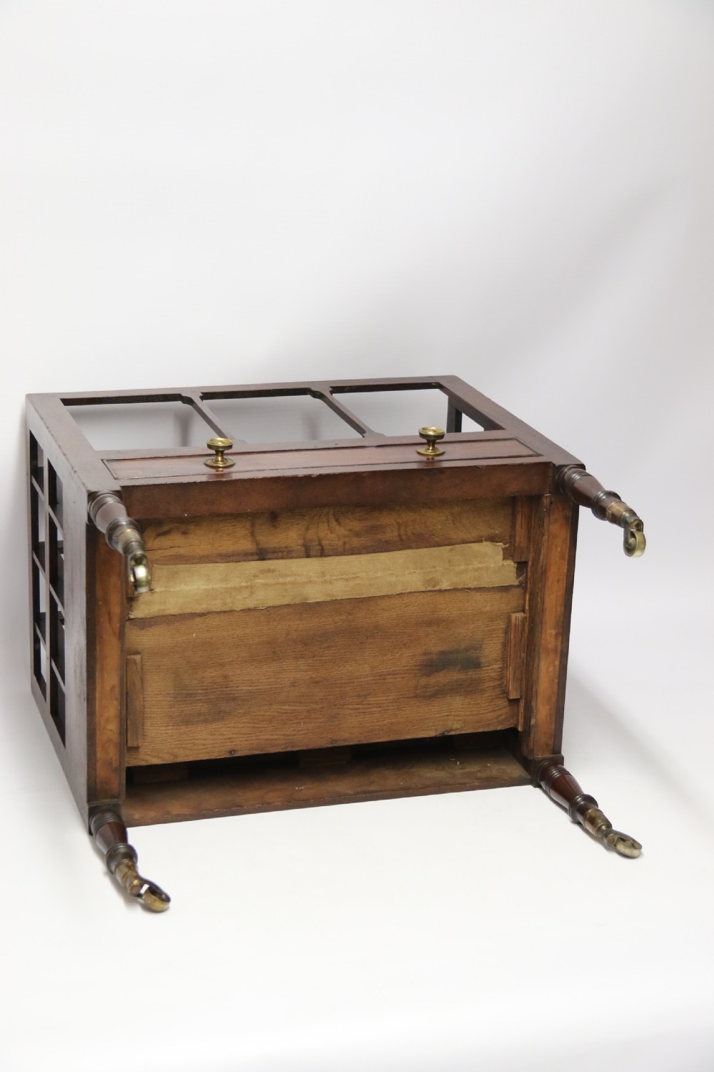 A dark mahogany George III Canterbury featuring slatted vertical partitions, a lower single drawer with brass ring handles, and turned legs resting on brass castors. View VII