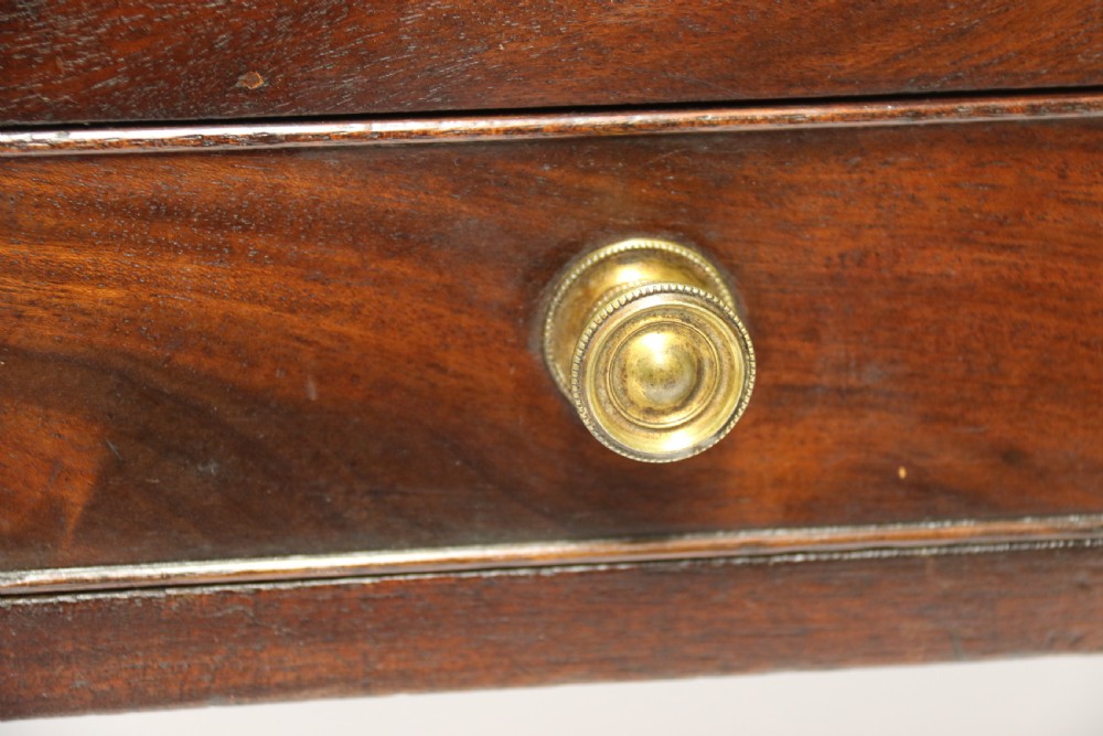 A dark mahogany George III Canterbury featuring slatted vertical partitions, a lower single drawer with brass ring handles, and turned legs resting on brass castors. View IX