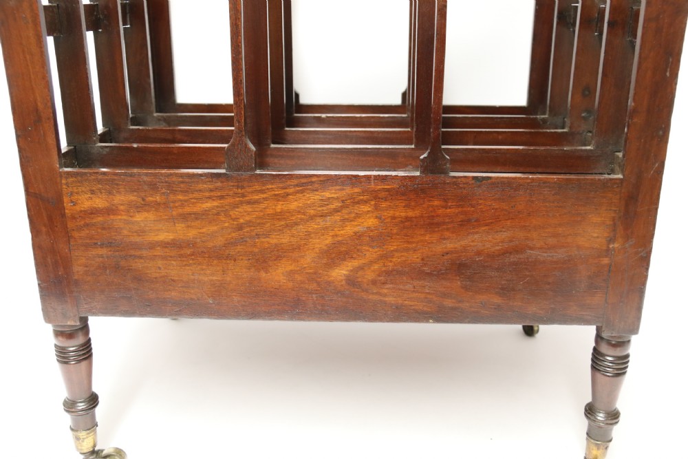 A dark mahogany George III Canterbury featuring slatted vertical partitions, a lower single drawer with brass ring handles, and turned legs resting on brass castors. View XII