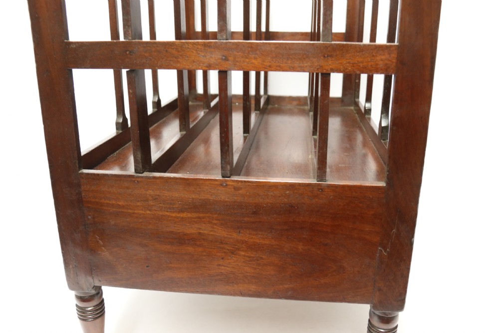 A dark mahogany George III Canterbury featuring slatted vertical partitions, a lower single drawer with brass ring handles, and turned legs resting on brass castors. View XIII