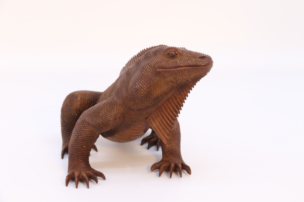 A hand-carved hardwood sculpture of an iguana featuring detailed scale patterns, a serrated dorsal crest, and a prominent dewlap in a warm brown finish. View III