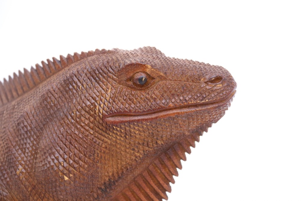 A hand-carved hardwood sculpture of an iguana featuring detailed scale patterns, a serrated dorsal crest, and a prominent dewlap in a warm brown finish. View XIV