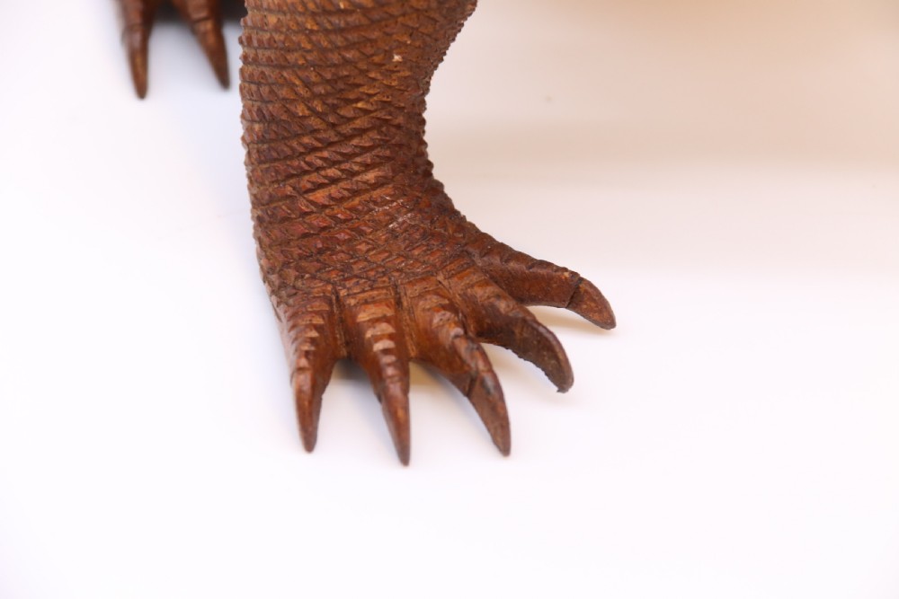 A hand-carved hardwood sculpture of an iguana featuring detailed scale patterns, a serrated dorsal crest, and a prominent dewlap in a warm brown finish. View XV
