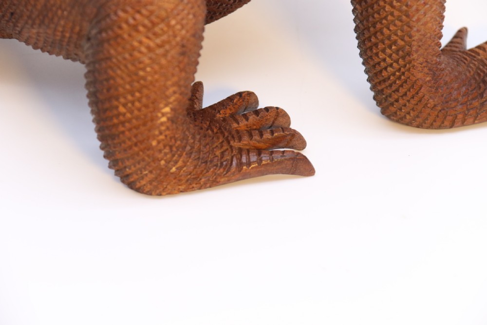 A hand-carved hardwood sculpture of an iguana featuring detailed scale patterns, a serrated dorsal crest, and a prominent dewlap in a warm brown finish. View XVI