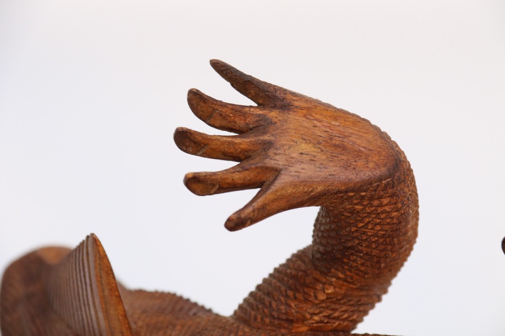 A hand-carved hardwood sculpture of an iguana featuring detailed scale patterns, a serrated dorsal crest, and a prominent dewlap in a warm brown finish. View XVIII