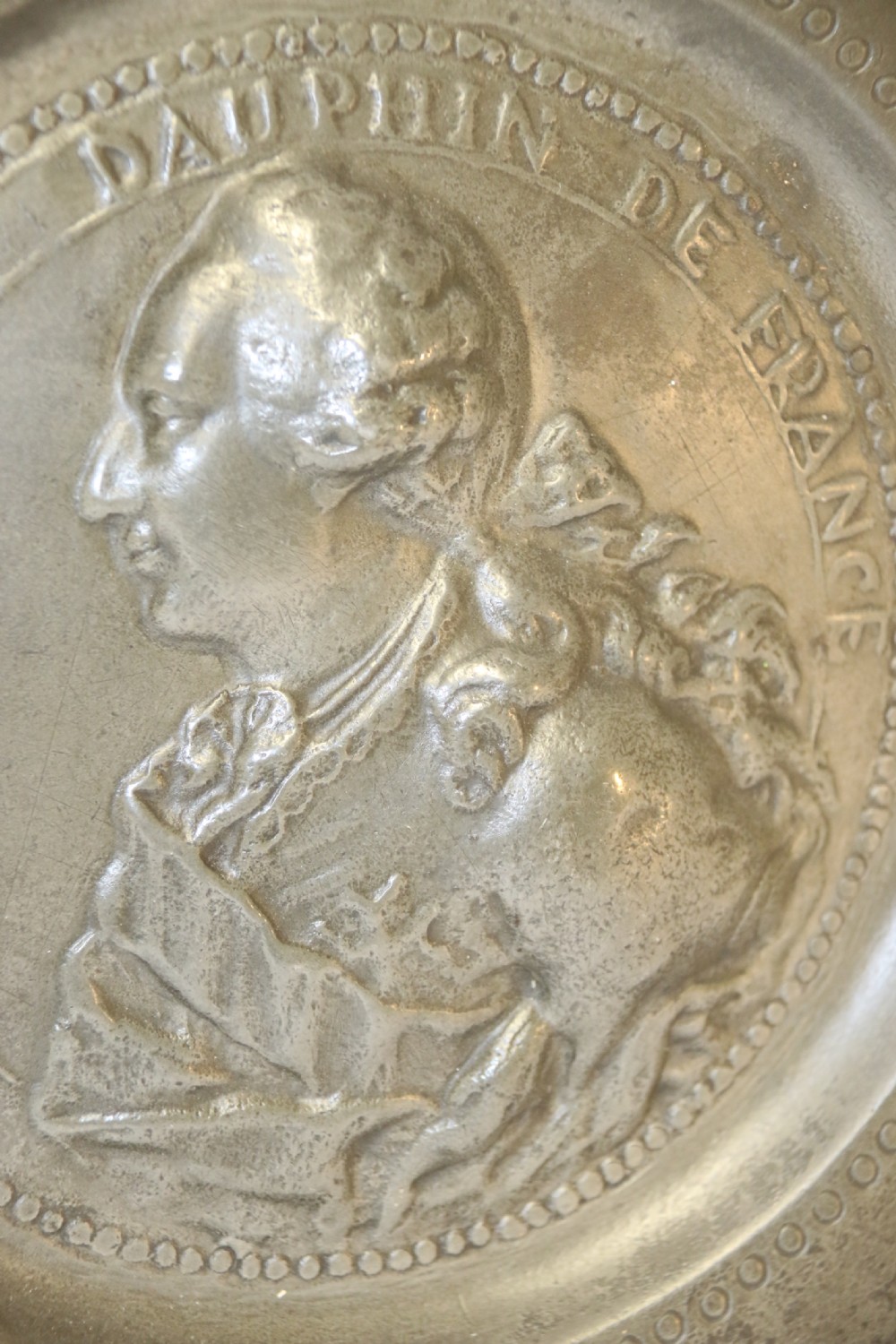 A pair of round silver grey pewter plates featuring raised profile relief portraits of Marie Antoinette and Louis XVI with beaded outer borders. View VI