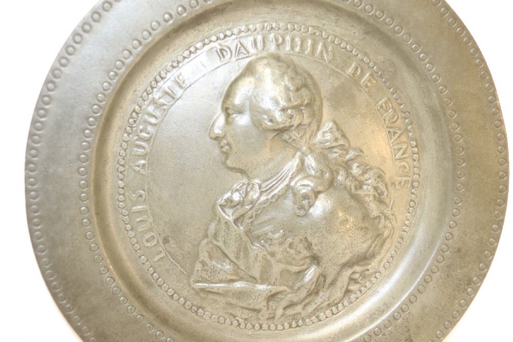 A pair of round silver grey pewter plates featuring raised profile relief portraits of Marie Antoinette and Louis XVI with beaded outer borders. View X